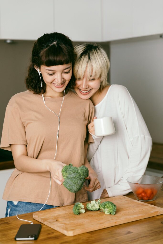 Woman Watching her Friend Cutting Broccoli